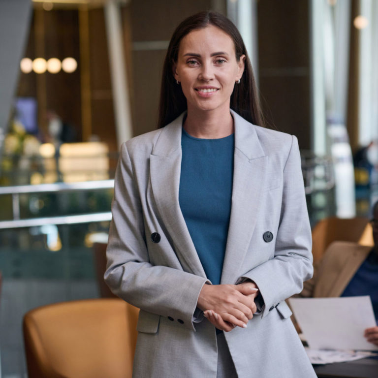 Portrait of businesswoman smiling at camera while having meeting with her colleagues in the hotel